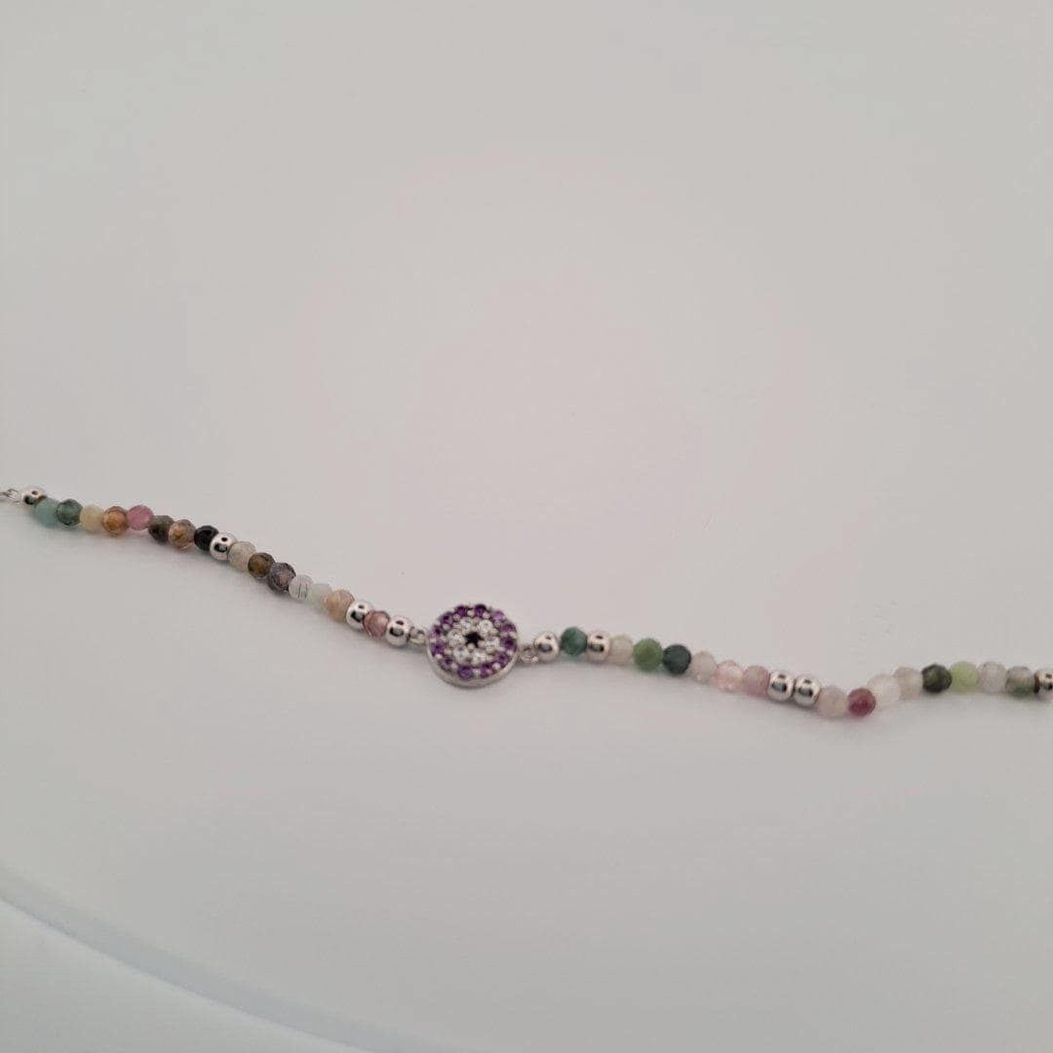 A bracelet made of colorful beads and a small circular charm with a purple center.