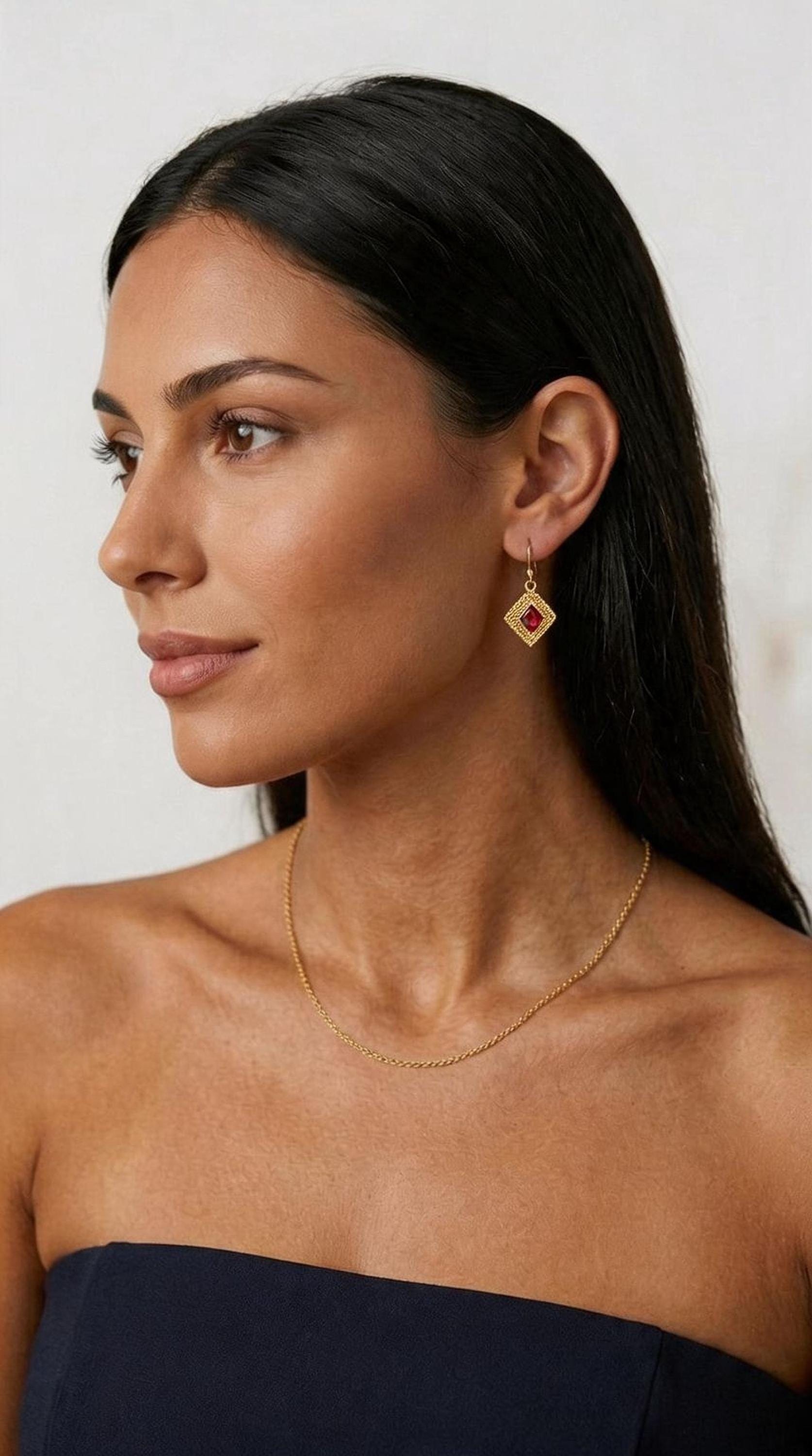 A woman with long dark hair wearing a gold necklace and earrings, looking to the side with a thoughtful expression.