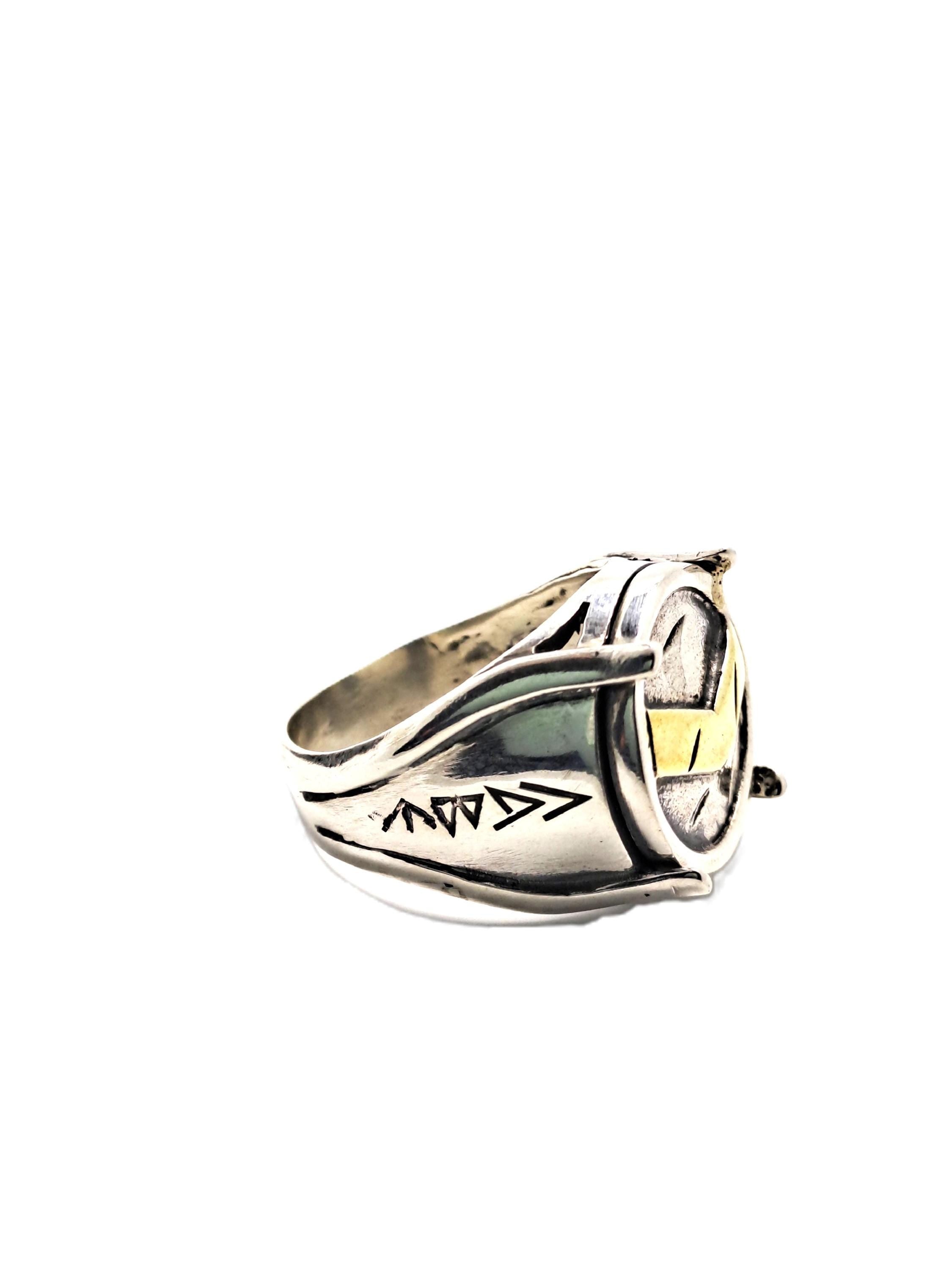 A silver ring with a unique design and a small clock face on it.