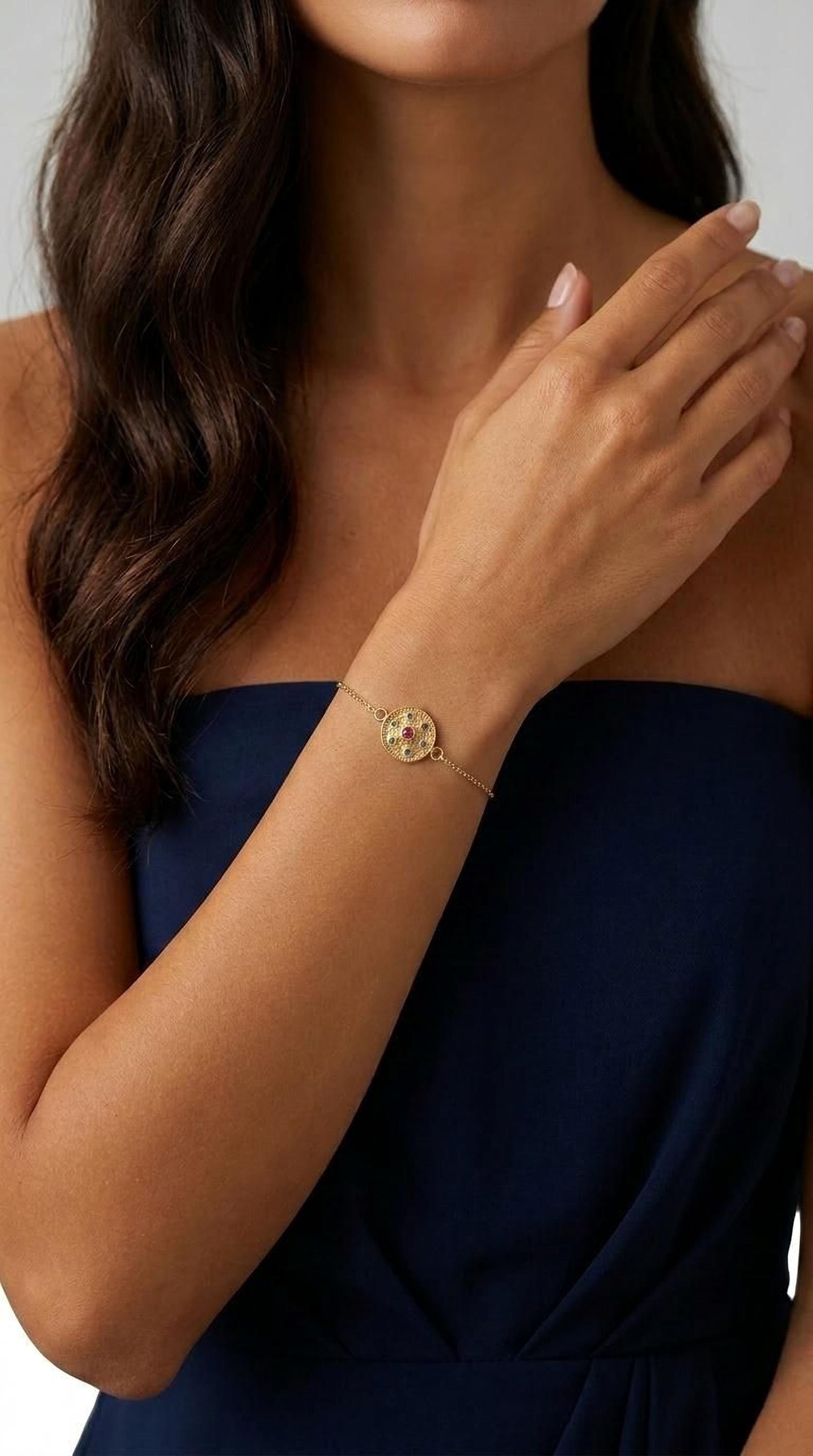 A woman wearing a navy blue strapless dress and a gold bracelet with a charm on her wrist.