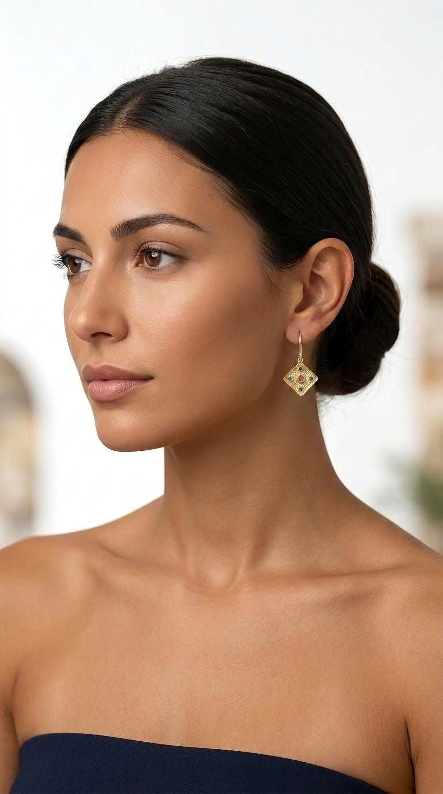 A woman with dark hair wearing a gold earring with a diamond design.