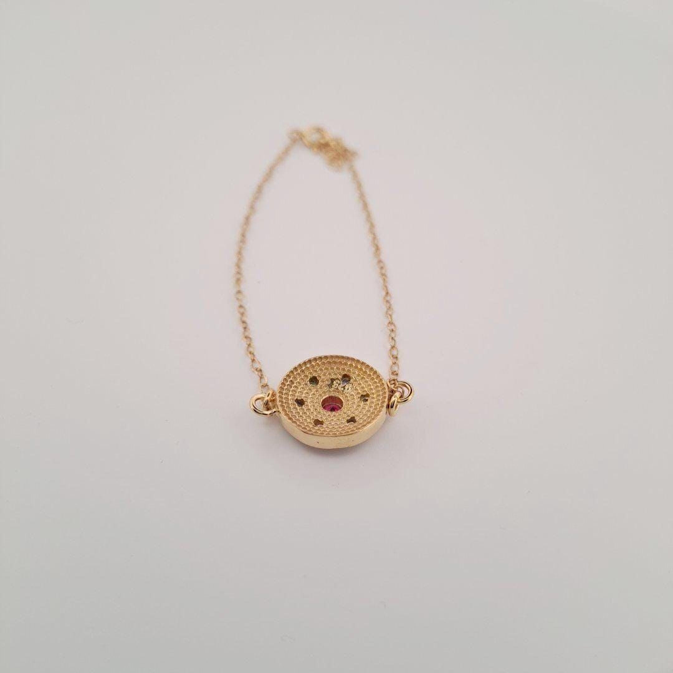 A gold-colored necklace with a round pendant featuring a small design.