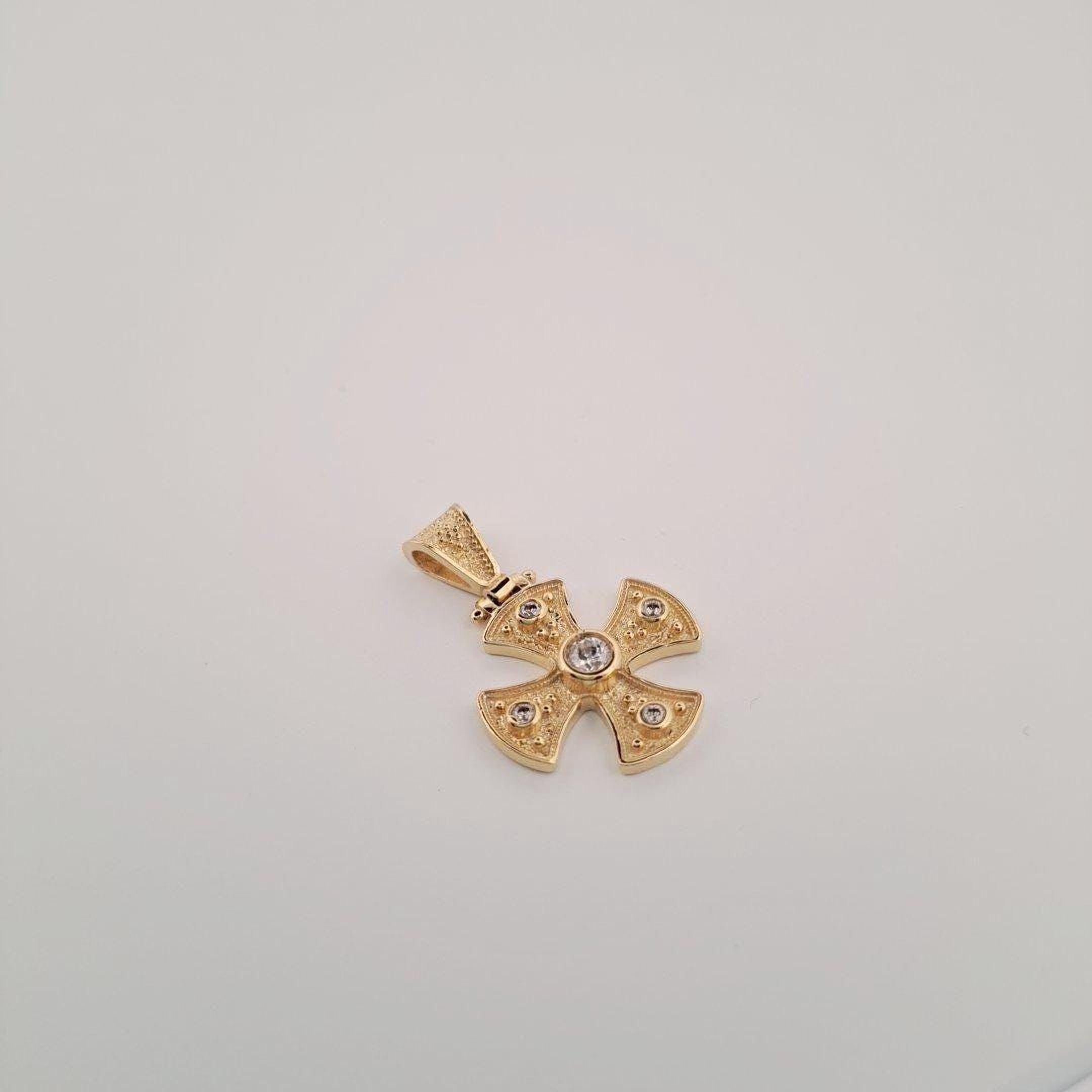 A gold-colored pendant in the shape of a cross with a small gemstone in the center.