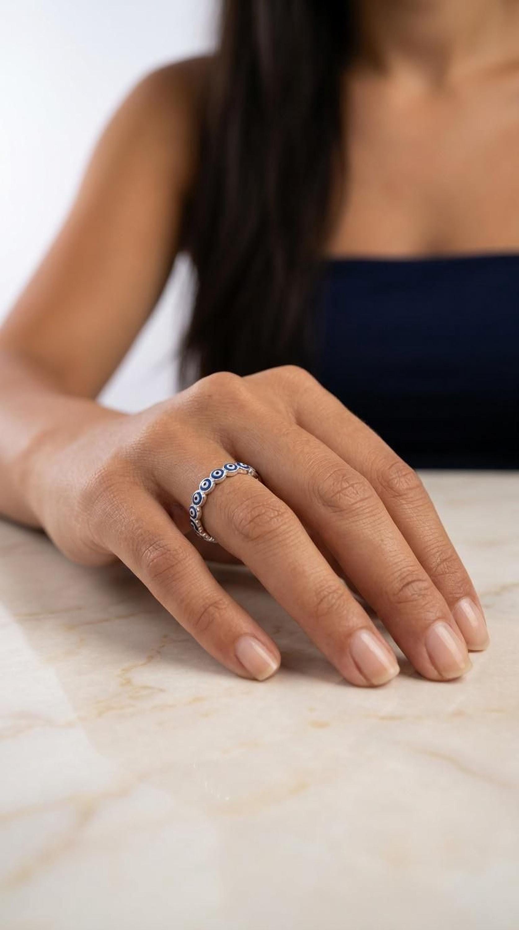 A close-up of a person's hand wearing a ring on the ring finger, with a blurred background.