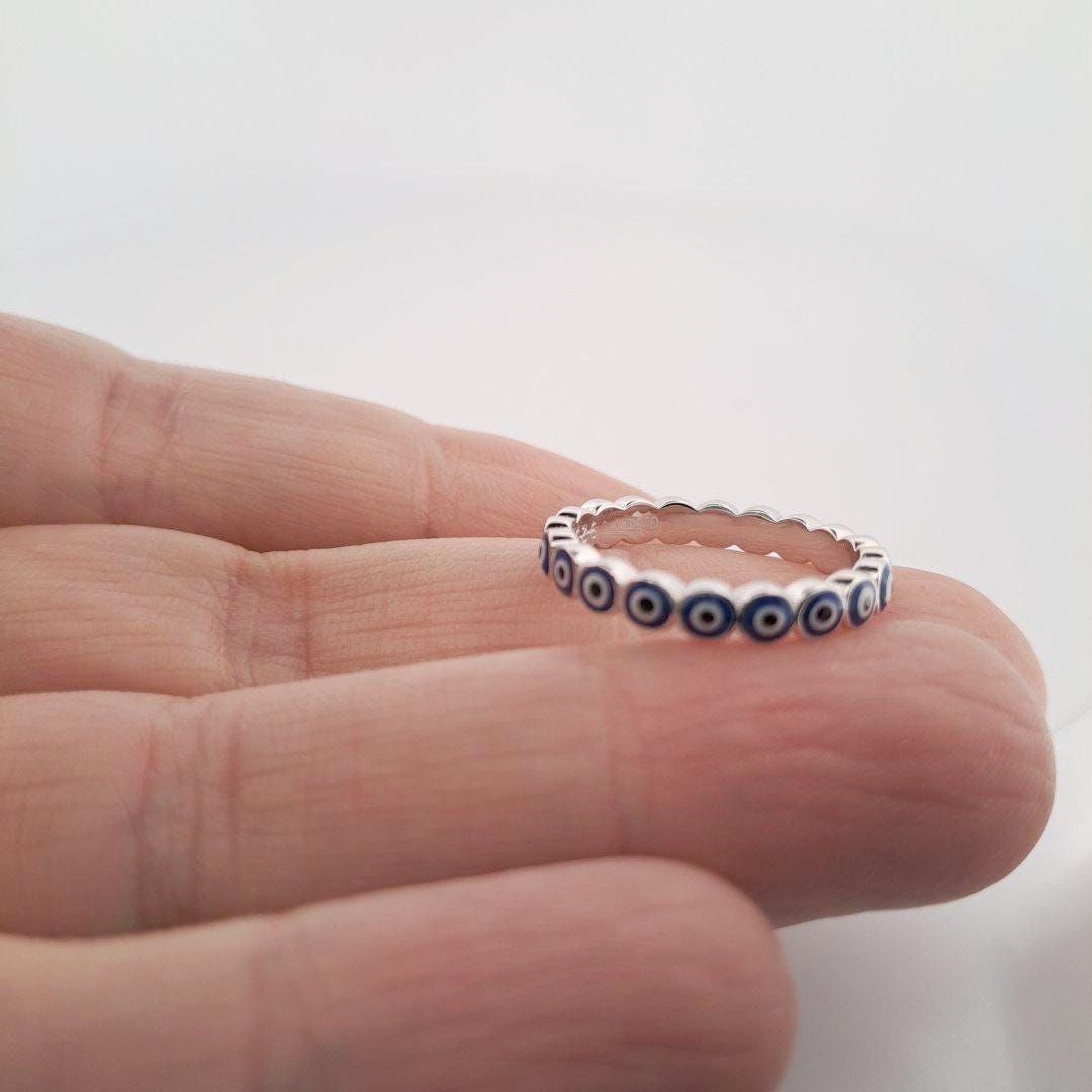 A hand holding a silver ring with blue circles on it.