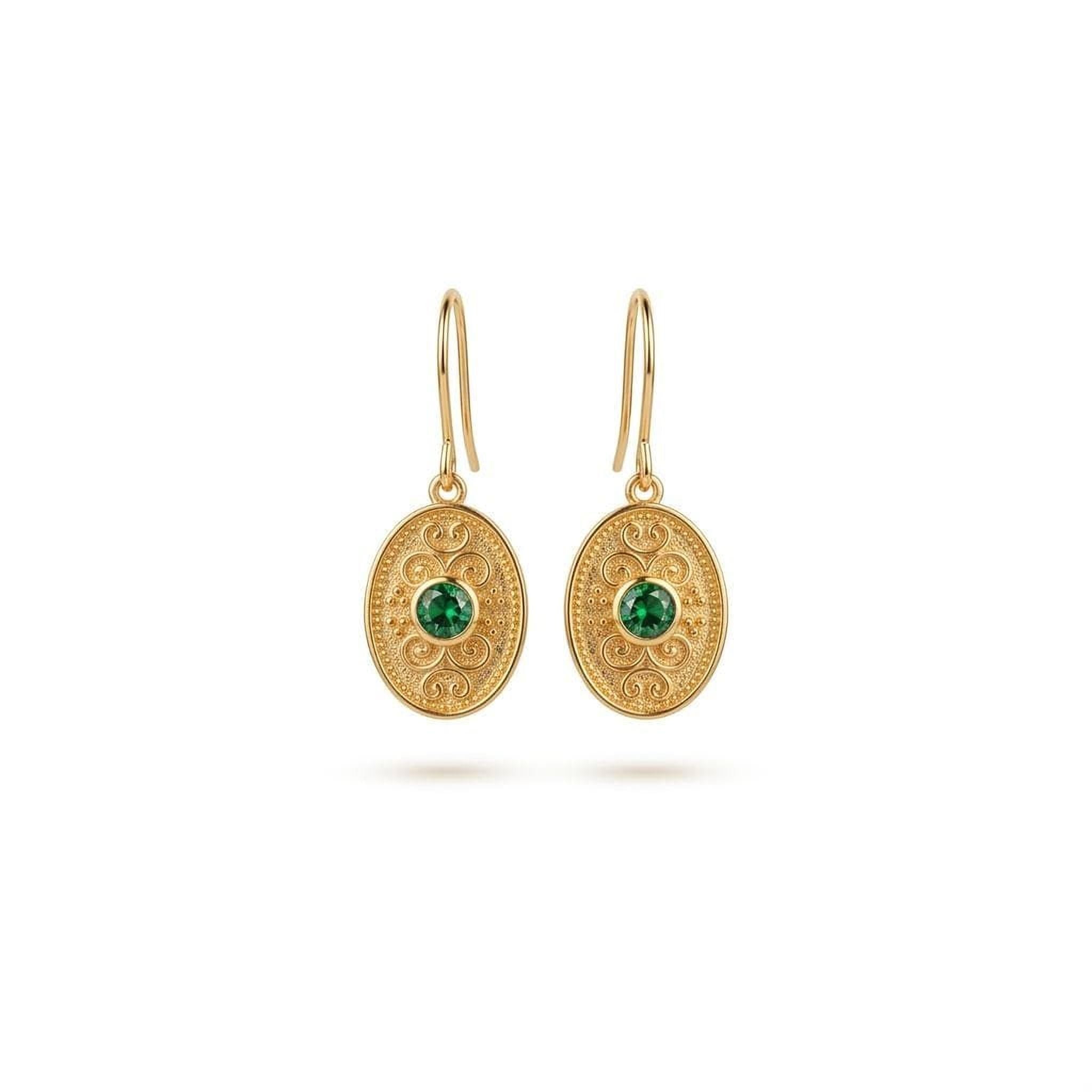 A pair of gold earrings with a green gemstone in the center, hanging from a hook.